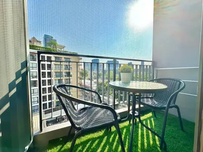 a balcony with two chairs and a table and a window at Bright & Spacious Apartment - Asoke in Bangkok