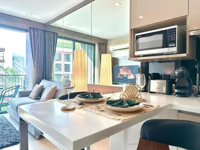 a kitchen and living room with a table and a couch at Bright & Spacious Apartment - Asoke in Bangkok