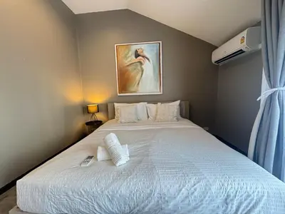 a bedroom with a white bed with a painting on the wall at Bangkok Phomphong Villa\u8054\u6392\u6cf0\u5f0f\u522b\u5885 in Bangkok