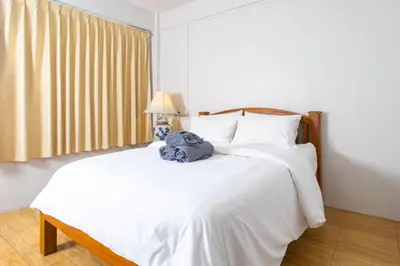 a bedroom with a white bed with a blue towel on it at TOM CAFE MY House in Thung Maha Mek