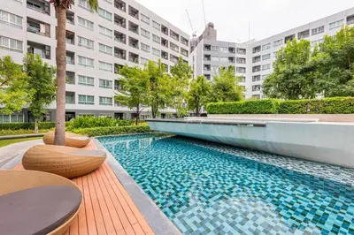 a swimming pool with tables and chairs in front of a building at Elio Del Ray Studio walk to BTS in Bangkok