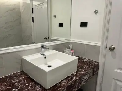 a bathroom with a white sink and a mirror at Elizabeth Hotel in Bangkok