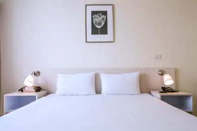 a bedroom with a large white bed with two lamps at Elizabeth Hotel in Bangkok