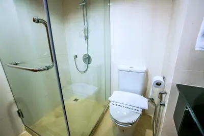 a bathroom with a glass shower and a toilet at Elizabeth Hotel in Bangkok