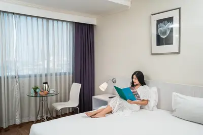 a woman sitting on a bed reading a book at Elizabeth Hotel in Bangkok