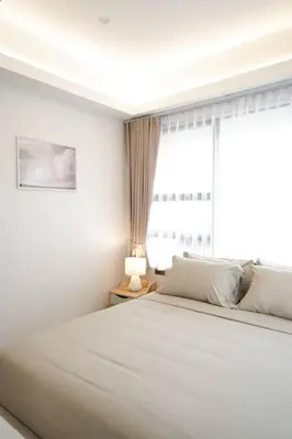 a white bedroom with a large bed and a window at Somewhere house in Bangkok
