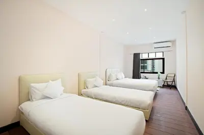 two beds in a hotel room with a desk at OH Homes - Samsen 12 in Bangkok