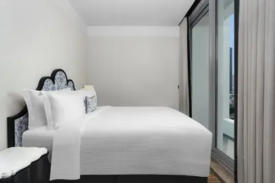 a white bedroom with a bed and a window at La Clef Bangkok by The Crest Collection in Bangkok
