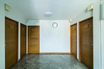 a hallway with wooden doors and a clock on a wall at XX GO INN Khaosan ตรอกข้าวสาร สนามหลวง in Bangkok