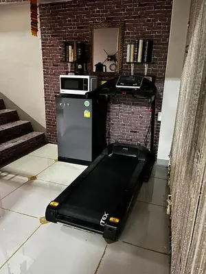 a treadmill in a living room with a microwave at โรงพักบางระมาด by ModiCoff Café in Sathani Ban Chim Phali