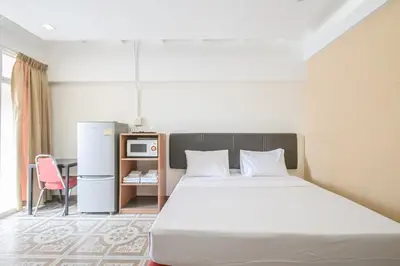 a bedroom with a bed and a table and a refrigerator at AC Habitat Bangkok in Bangkok