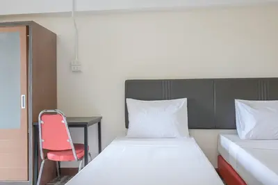 a bedroom with two beds and a red chair at AC Habitat Bangkok in Bangkok