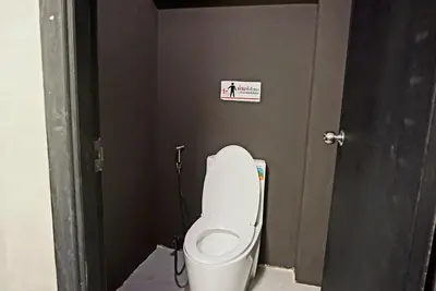 a bathroom with a toilet with a sign on the wall at Silom Soi 3 Hash Hostel in Bangkok