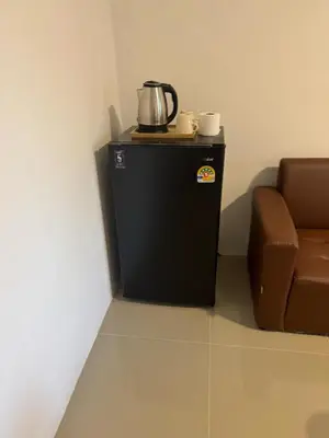 a coffee pot on top of a refrigerator next to a chair at ณัฐพิมลเพลส์ 3 in Bangkok Yai