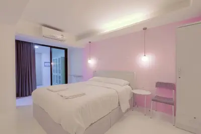a white bedroom with a large bed and a table at 24 degree hotel & hostels in Bangkok