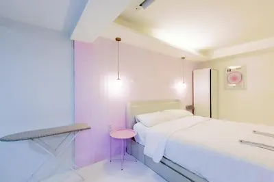 a white room with a bed and a pink stool at 24 degree hotel & hostels in Bangkok