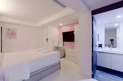 a white bedroom with a large bed and a sink at 24 degree hotel & hostels in Bangkok