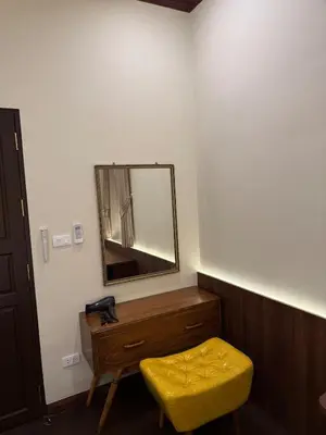 a bathroom with a mirror and a yellow stool at Luan Heritage Surawong in Bangkok