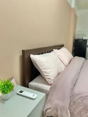 a bed with white pillows and a table with a phone at La Maison 230 in Ban Khlong Samrong