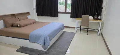 a bedroom with a bed and a table and a desk at Homey Place in Ban Song Hong
