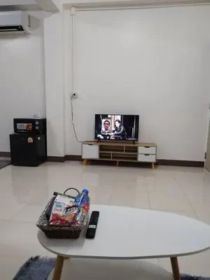 a living room with a table and a tv at Homey Place in Ban Song Hong