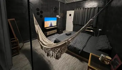 a hammock in a room with a bed and a tv at Stay Strays Hostel in Bangkok