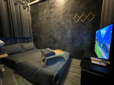 a room with a bed and a tv and a table at Stay Strays Hostel in Bangkok