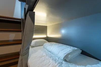 a small bedroom with a bed with white sheets at The Chedee Krungthep in Bangkok