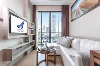 a living room with a white couch and a large window at Adelphi Forty-Nine in Bangkok