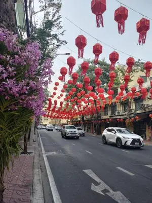 a street with cars driving down a street with red lanterns at The Burapa Rooms in Bangkok