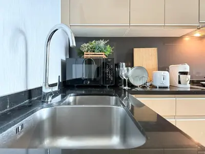 a kitchen with a sink and a microwave at Roomy Modern 2BR - Ultra Fast WiFi - BTS Phrom Phong in Bangkok