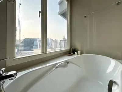 a white bath tub in a bathroom with a window at Roomy Modern 2BR - Ultra Fast WiFi - BTS Phrom Phong in Bangkok