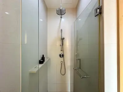 a shower with a glass door in a bathroom at Roomy Modern 2BR - Ultra Fast WiFi - BTS Phrom Phong in Bangkok