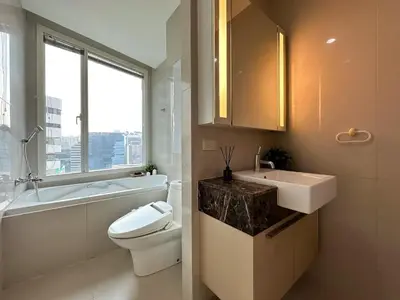 a bathroom with a sink and a toilet and a window at Roomy Modern 2BR - Ultra Fast WiFi - BTS Phrom Phong in Bangkok