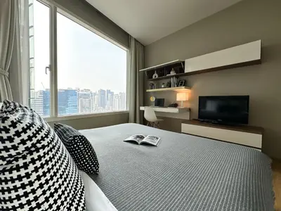 a bedroom with a bed with a television and a window at Roomy Modern 2BR - Ultra Fast WiFi - BTS Phrom Phong in Bangkok
