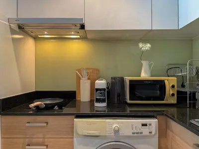 a kitchen with a dishwasher and a microwave on a counter at Luxurious High-Rise - Ultra Fast Wifi - MRT Petchaburi in Bangkok
