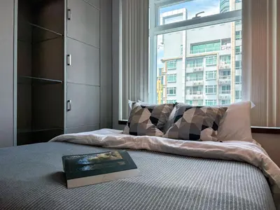 a bed with a book on it with a window at Luxurious High-Rise - Ultra Fast Wifi - MRT Petchaburi in Bangkok