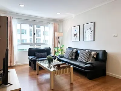 a living room with a black leather couch and a coffee table at Upscale Expansive 2BR - Ultra Fast Wifi - Phrom Phong in Bangkok