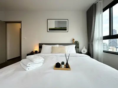 a bedroom with a large white bed with towels on it at Expansive Stylish 2BR - Ultra Fast Wifi - Asoke in Bangkok