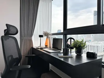 a desk with a laptop and a chair in front of a window at Expansive Stylish 2BR - Ultra Fast Wifi - Asoke in Bangkok