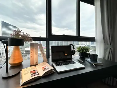 a desk with a laptop computer and a book at Expansive Stylish 2BR - Ultra Fast Wifi - Asoke in Bangkok