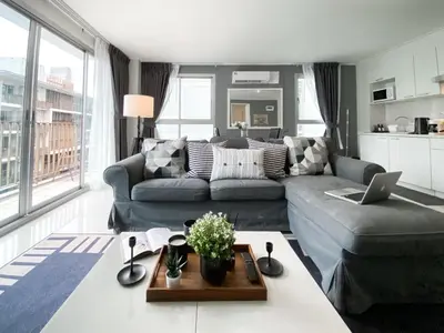 a living room with a couch and a laptop on a table at Exclusive Urban Apt 1BR - Ultra Fast Wifi - Thong Lo in Bangkok