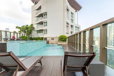 a swimming pool with two chairs next to a building at 2Br, Good view, BTS Chitlom, BKK in Bangkok