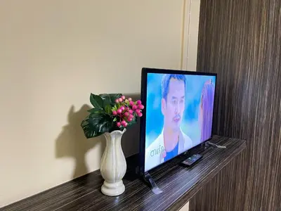 a television sitting on a table with a vase of flowers at Ordinary Salaya in Sathani Sala Ya