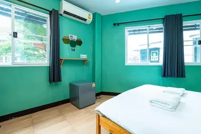 a green room with a bed and two windows at xx GO INN The Giant Swing เสาชิงช้า กรุงเทพ in Bangkok