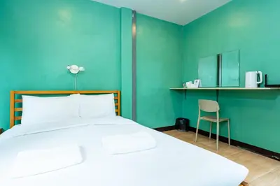 a bedroom with a large white bed and a chair at xx GO INN The Giant Swing เสาชิงช้า กรุงเทพ in Bangkok