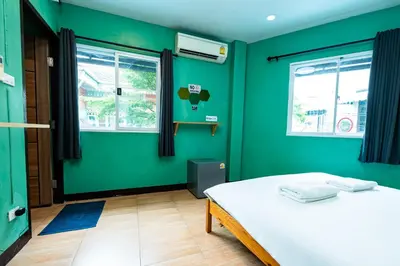 a green room with a bed and two windows at xx GO INN The Giant Swing เสาชิงช้า กรุงเทพ in Bangkok