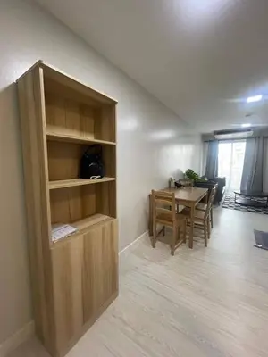 a living room with a table and a wooden book shelf at MeStlye BangNa - Baan Win in Bangna
