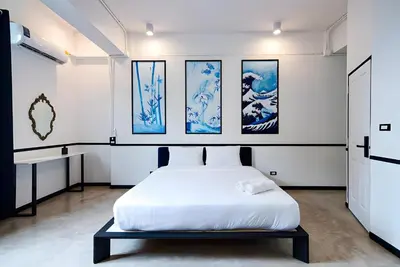 a bed in a room with paintings on the wall at xx The Character Yaowarat เดอะ คาแรคเตอร์ เยาวราช ตรอกข้าวสาร in Samphanthawong