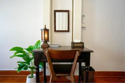 a desk with a chair and a mirror and a plant at Nivas Wanit 2BR 1SFB Yaowarat MRT EntireHome 80SQM in Bangkok